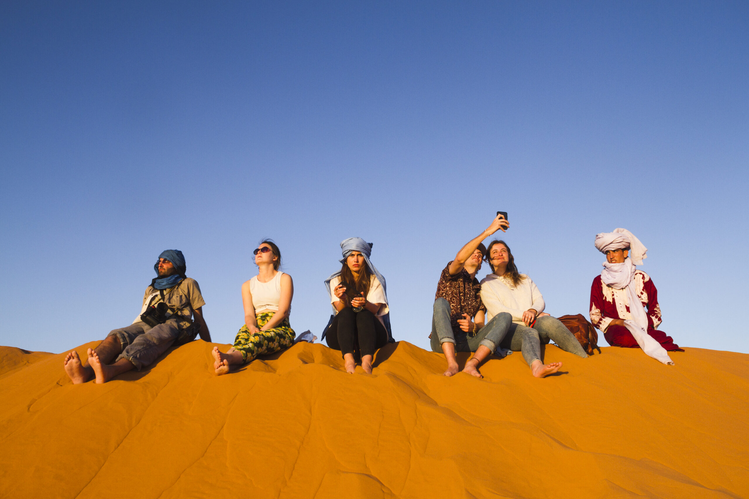 group people sitting top dune scaled
